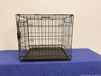 Frontal view of black wire dog crate with tray inserted