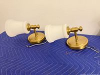 Pair of brass sconces lying on side showing shades and wiring