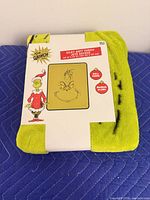 Front view of packaged Grinch throw blanket