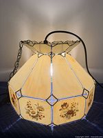 angled view of stained glass pendant lamp showing cream panels and floral sections