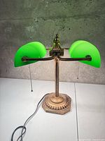 Full view of brass-tone base and twin green glass shades