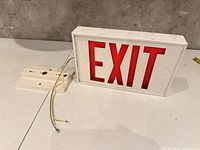 Exit sign front view with mounting bracket and wires