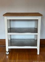 Front view of white Stenstorp cart with wood top and two metal shelves