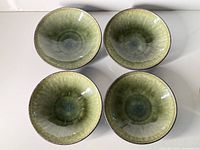 Top view of four green glazed bowls showing interior glaze and wear