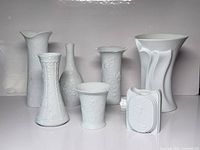 Front view of all seven white bisque porcelain vases