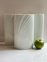 Three white porcelain vases with apple for scale