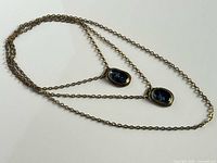 Full view of double-strand brass necklace showing both blue glass pendants and clasp