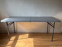 Full view of one grey folding table unfolded and standing