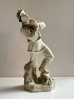 Full view of porcelain Hutsul figurine showing stance, attire and broken pipe end