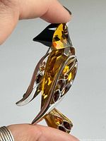 Profile of sterling silver bird brooch with amber and garnet crystals