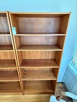 Front view of tall teak veneer bookcase with four shelves
