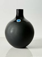 Front view of round dark green/black crystal vase with matte body and glossy neck, Sasaki label visible