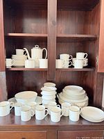 Cabinet view showing full dinnerware set: plates, teapot, mugs, serving bowl