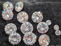 Group of loose cubic zirconia stones on black background showing size variety and faceting