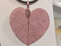 Front view of rose-gold tone natural leaf pendant on black cord