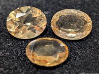 Three oval faceted citrine gemstones on dark background
