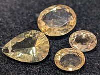 Four loose faceted citrines on dark background