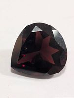 Front view of dark red faceted pear-shaped garnet