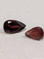 Two pear-shaped garnet gemstones on white background