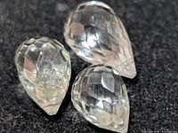 Three faceted pear-shape green amethyst stones on black background