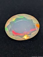 close-up of oval faceted opal showing multicolour play