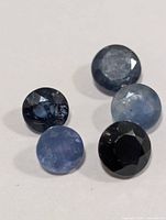 Close view of five round faceted sapphires displaying color variations