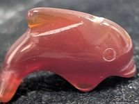 Side view of translucent red-orange carnelian dolphin figurine showing overall shape and polish