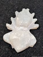 Front view of white opal carving showing floral shape and polished finish