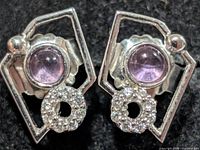 Front view of both earrings showing amethyst cabochons, pavé circle and geometric frames