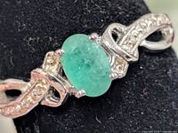 Front view showing oval emerald, prongs, accent stones, twisted shoulders