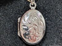 Front view of oval sterling silver locket with floral design