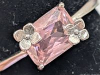 Close-up of pink CZ and flower accents on silver ring