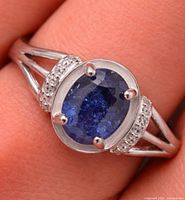 Close-up of ring on finger showing sapphire, prongs, accent stones