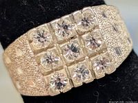 Front view showing grid of twelve clear stones and textured band detail