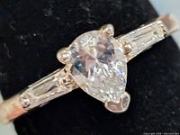 Front view of ring showing pear-cut cz and baguette shoulders