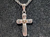 Close-up of cross pendant front showing diamond and heart bezel detail