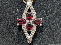 Front view of silver pendant showing four garnets and bead accents