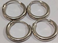 Top view of four silver hoop earrings arranged in a square