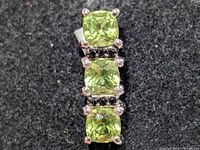 Front view of silver pendant with three peridot stones