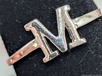 Front view of silver ring showing raised M initial