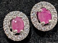 Front view of both silver ruby earrings showing oval rubies and surrounding clear stones