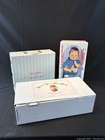 Three original boxes: Alexander Calendar Girls case, Tiny Thumbelina box, Adora Name Your Own Baby carton