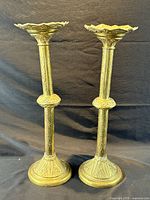 Front view of both brass candleholders standing side by side