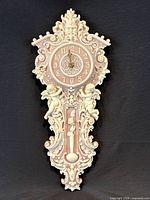 Full front view of ornate pink and cream wall clock