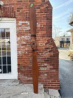 Front view of full propeller leaning against brick wall