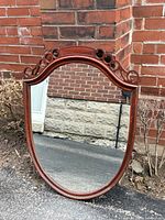 Front view of shield mirror showing carved wood crest and overall shape