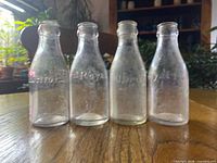 Four clear glass embossed juice bottles standing on table