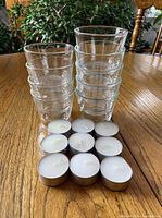 two stacks of nine total clear glass votive holders with ten tealights arranged in front
