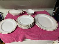 All pieces laid out: lidded casserole, dinner plates, small bowl, large platter