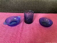 Three cobalt blue glass pieces on pink surface showing overall lot